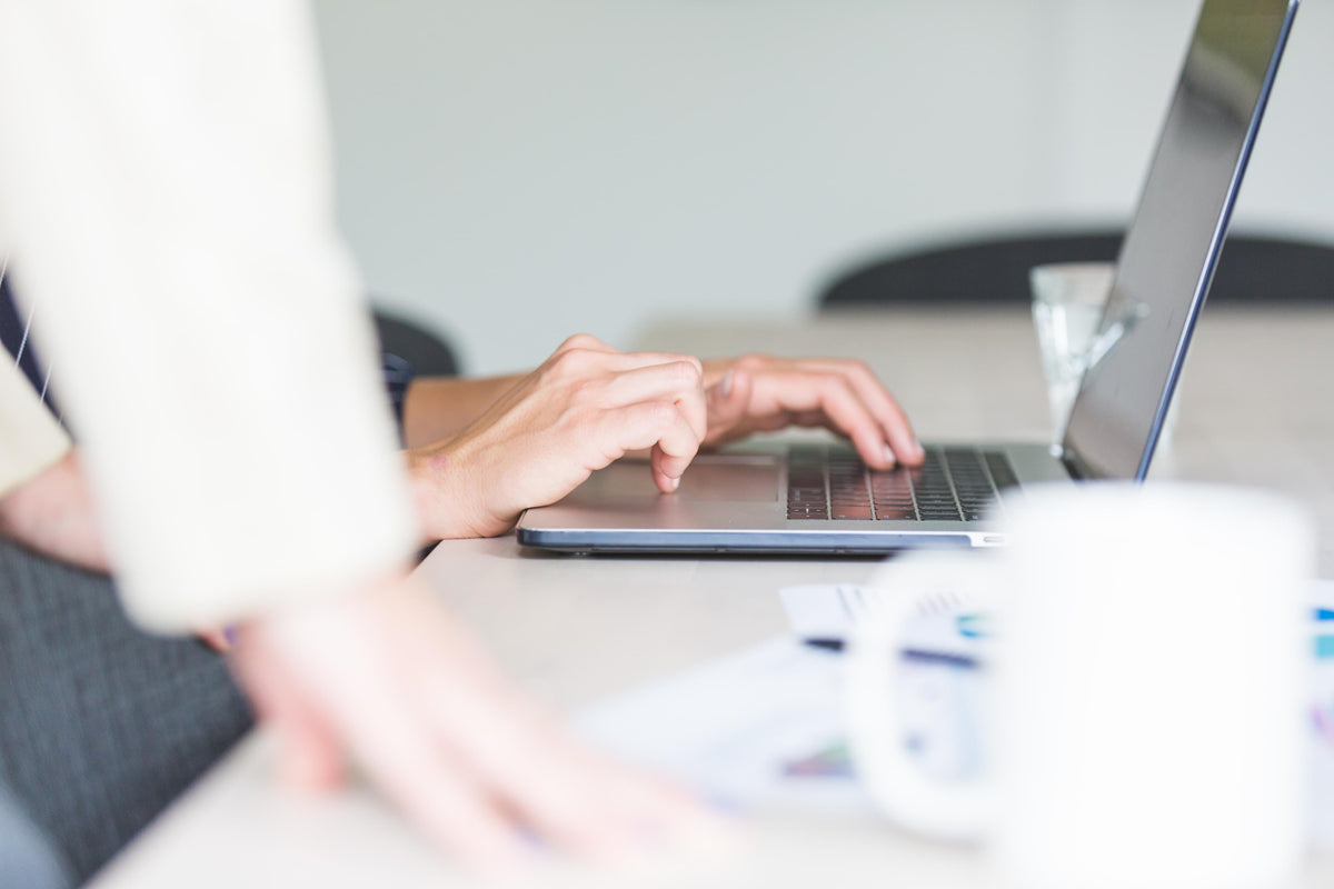 Hands using a computer in an office, representing Verelle Tenant Screening by The Verelle Group for background checks and tenant verification.